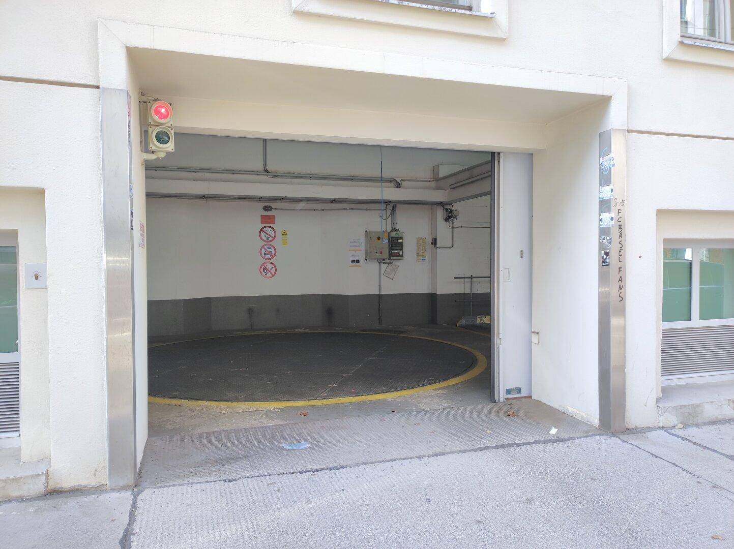 Außenansicht der Tiefgarageneinfahrt von der Straße, mit Ampel und Gebäudefassade.