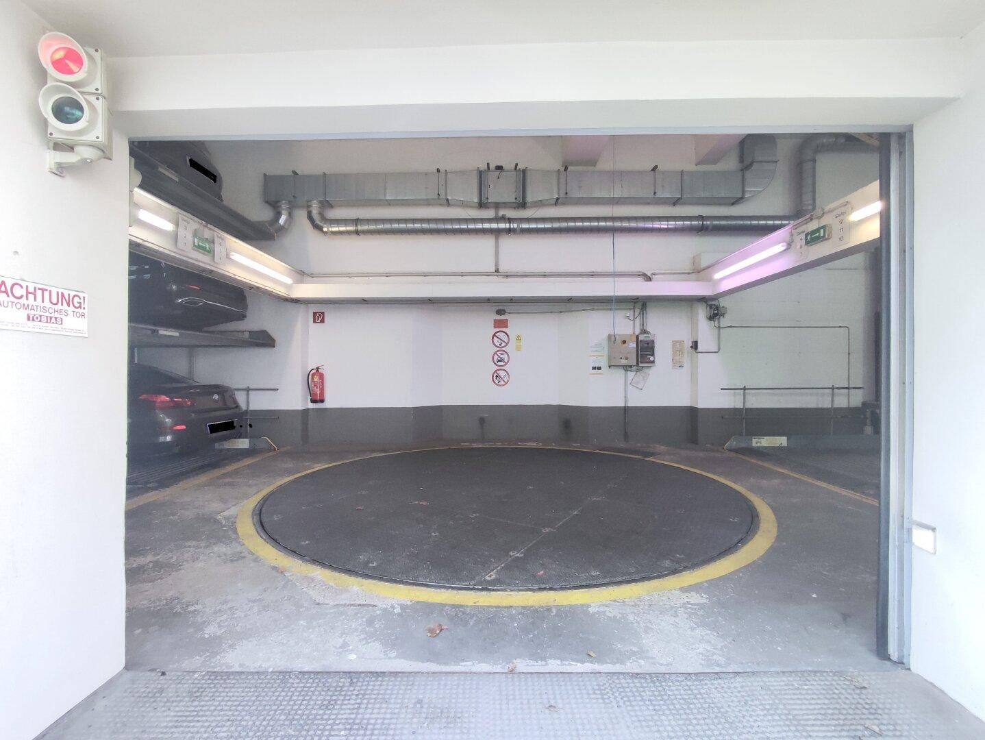 Einfahrt in die Tiefgarage mit Autodrehbühne und mechanischem Parksystem, von außen gesehen.