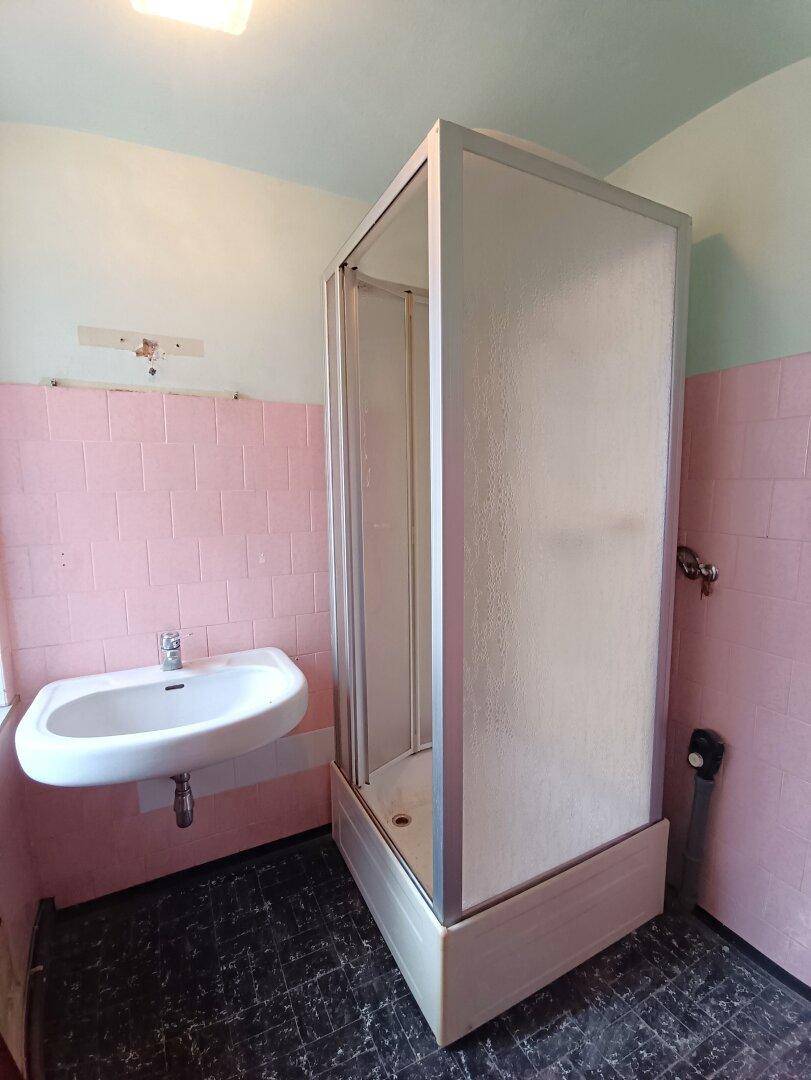 Badezimmer mit rosa Fliesen, Waschbecken und einer Duschkabine.