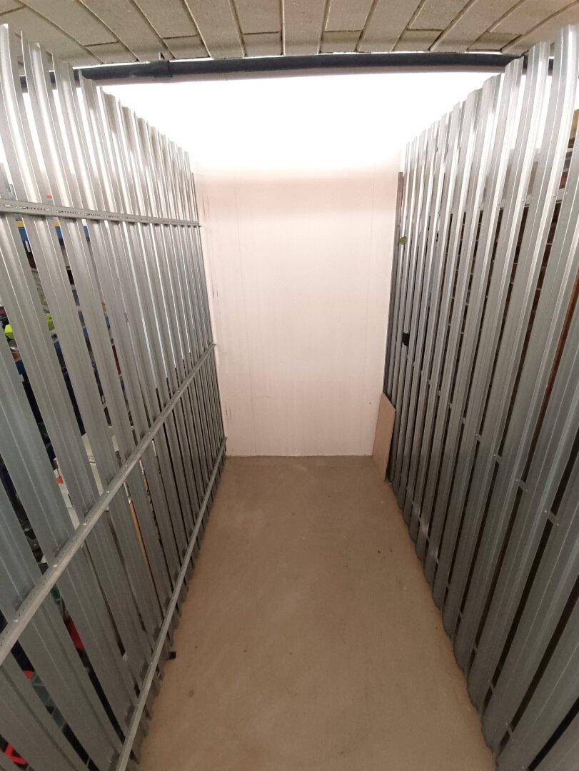 Heller Kellergang mit individuellen Abstellboxen, ideal für zusätzlichen Stauraum.