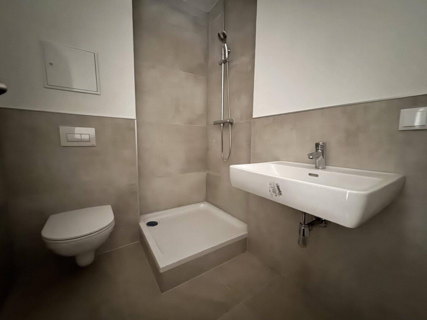 Modernes Badezimmer mit Duschkabine, wandhängendem WC und einem einzelnen Waschbecken.