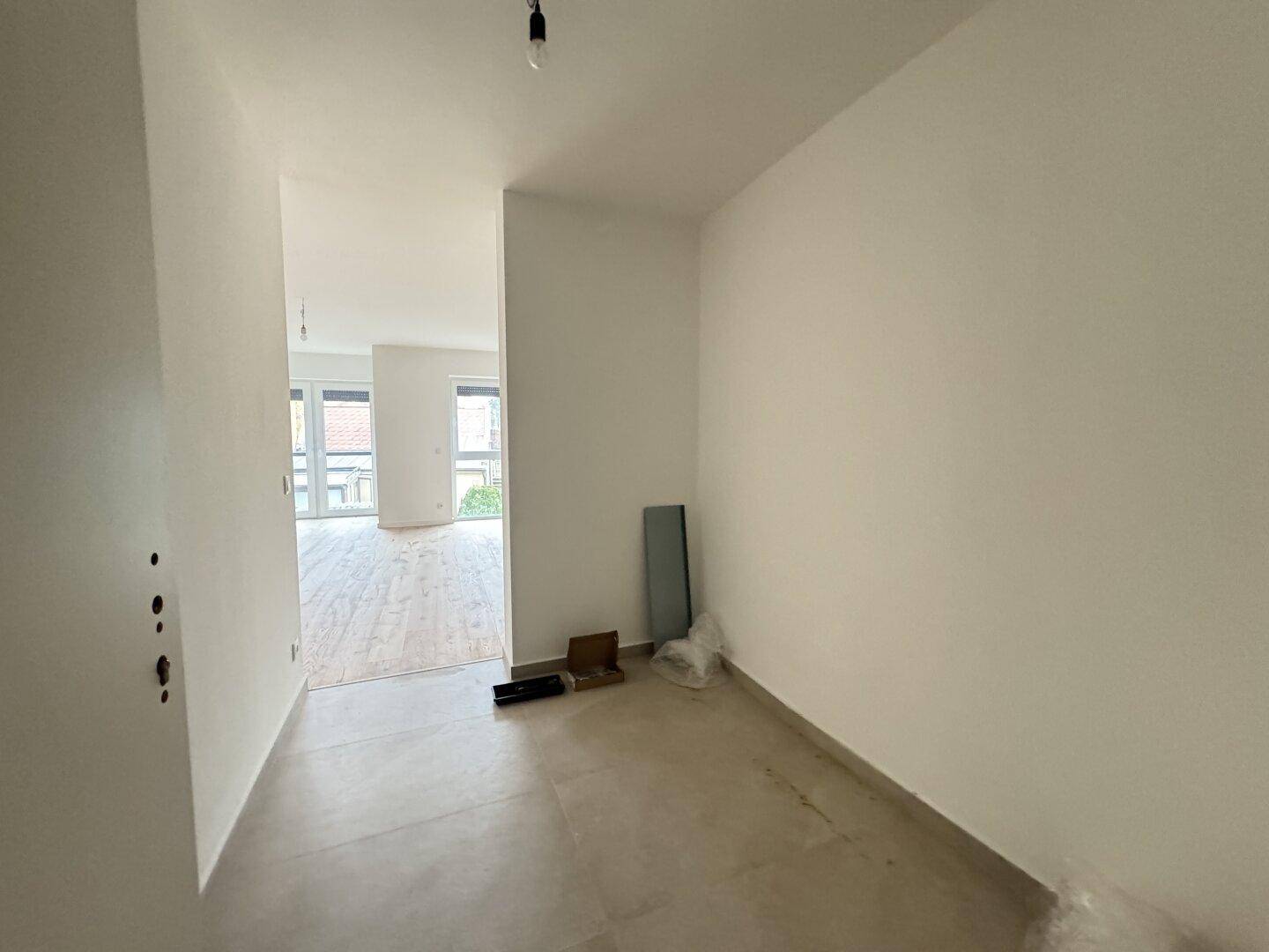 Heller Flur mit Fliesenboden, der zu den Wohnbereichen der neuen Wohnung führt.