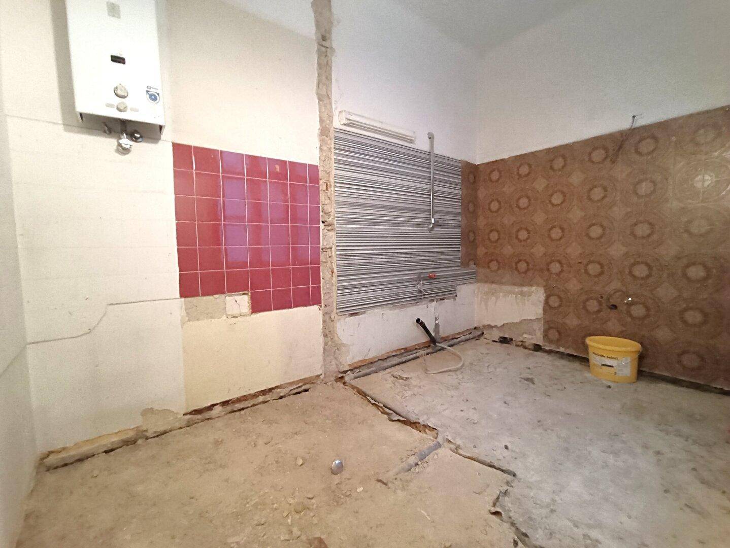 Küche in Renovierung mit Gastherme und teilweise gefliesten Wänden, bereit für den Umbau.