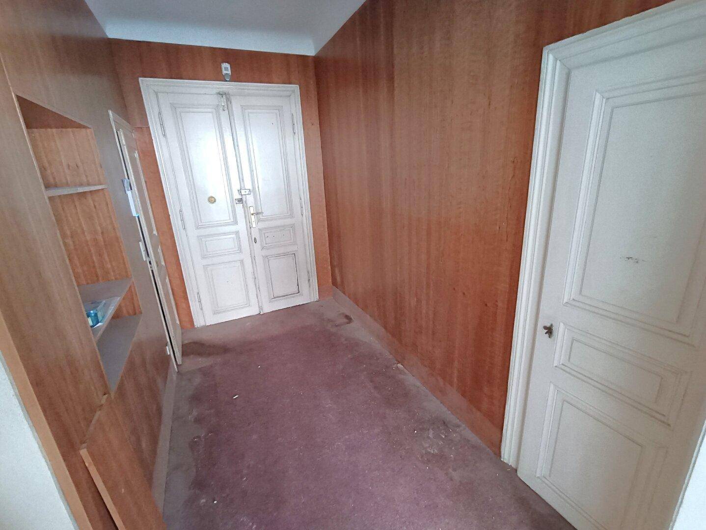 Flur mit Holzverkleidung und klassischen Doppeltüren, der auf eine Restaurierung wartet.
