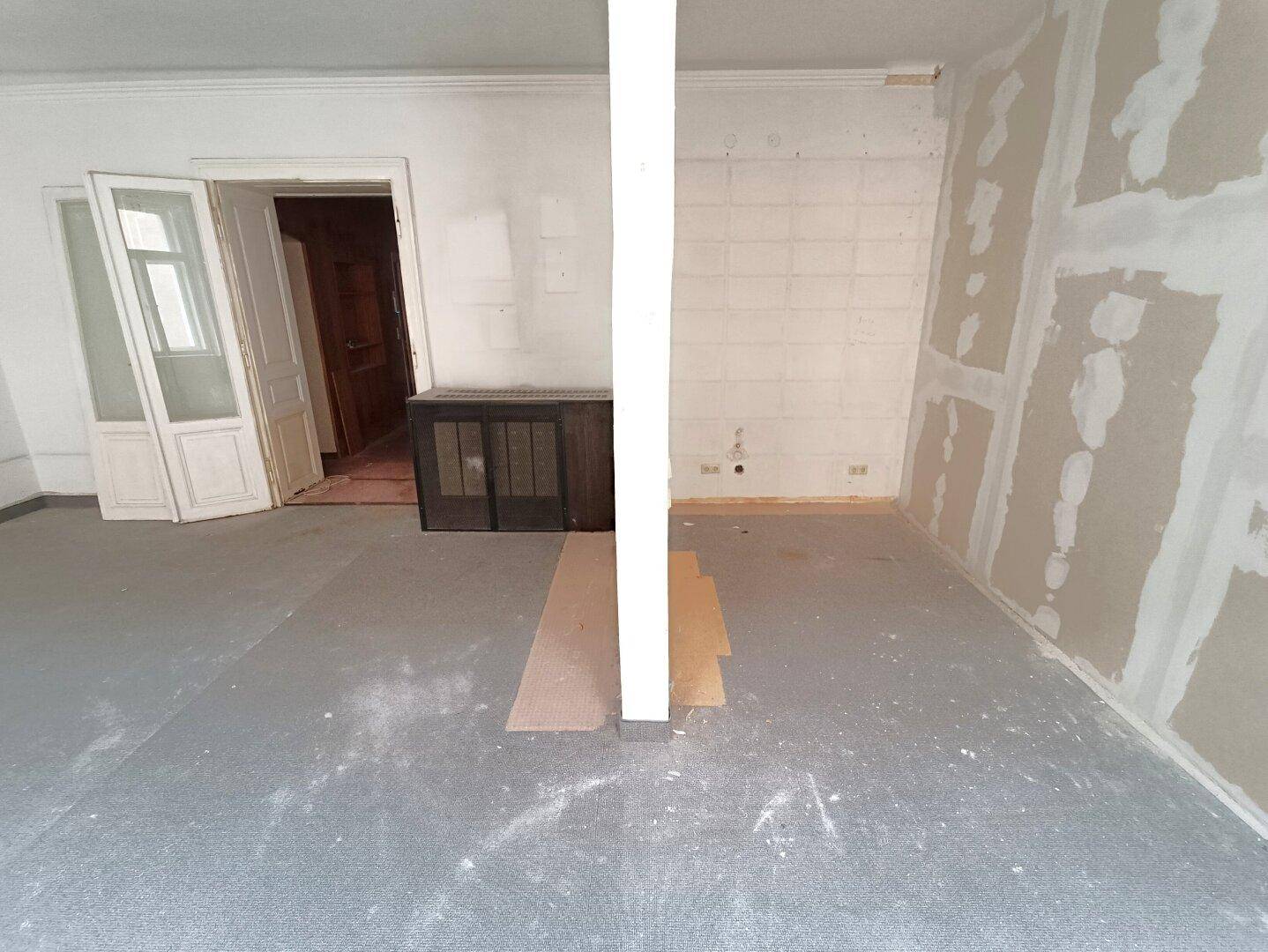 Heller Wohnraum mit Teppichboden und einem eingebauten Schrank, der renoviert werden muss.