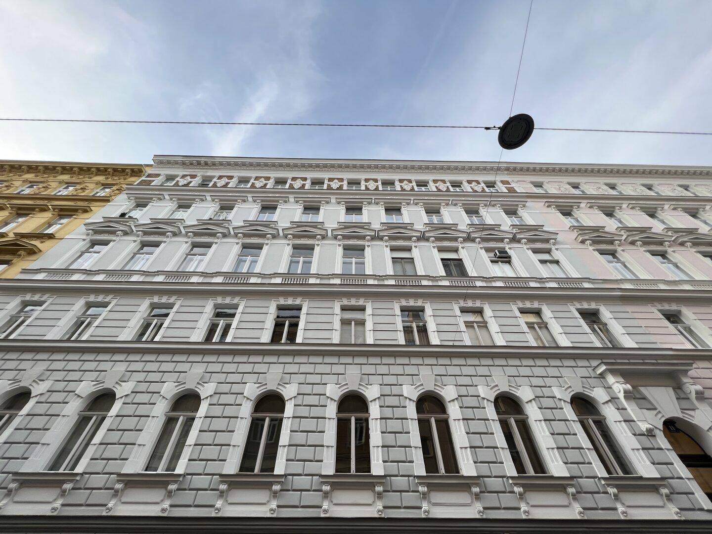 Prächtige Fassade eines Altbaus mit vielen Fenstern und dekorativen Elementen.