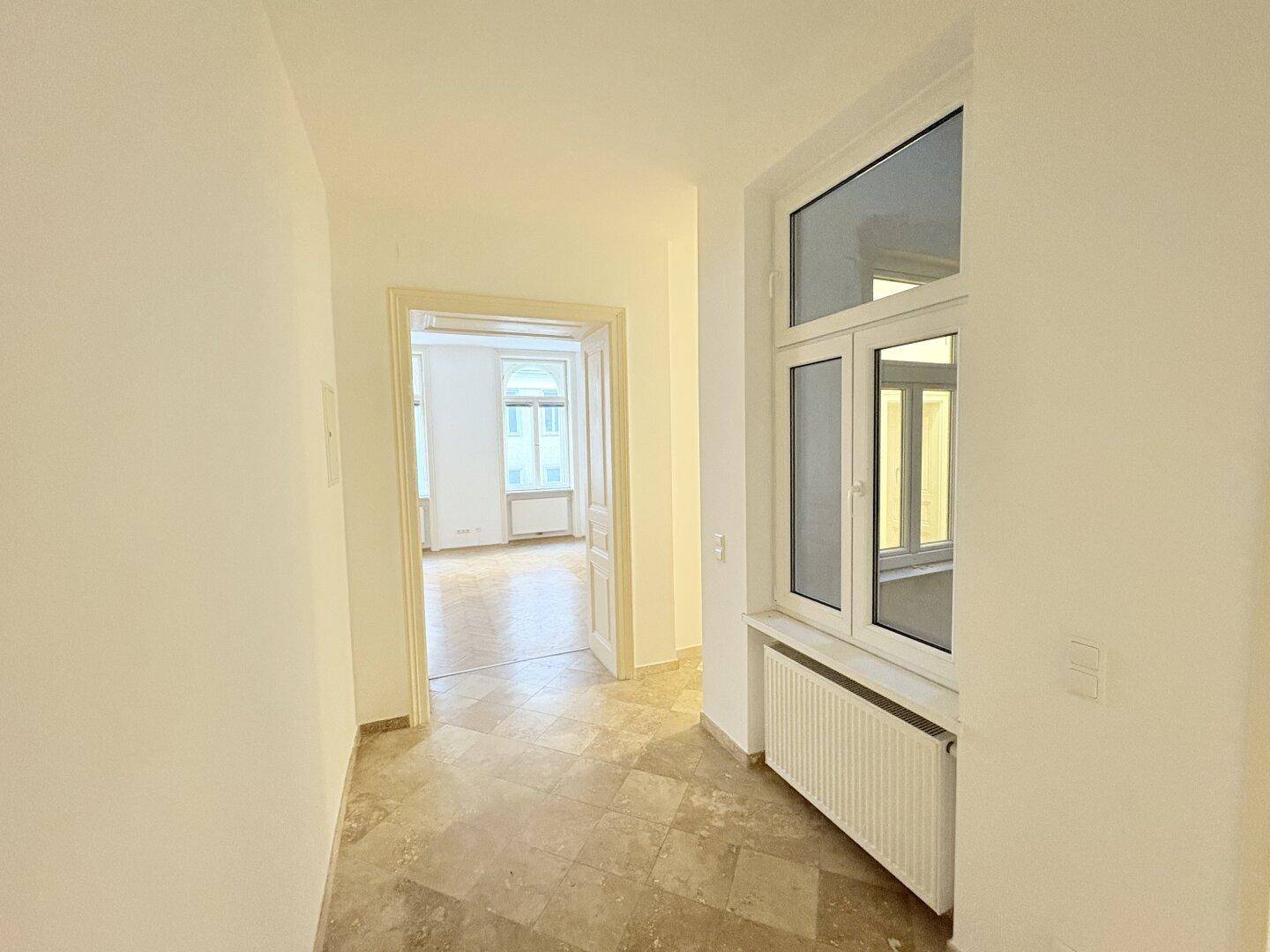 Flur mit Fliesenboden und Blick in ein weiteres Zimmer mit Parkettboden.