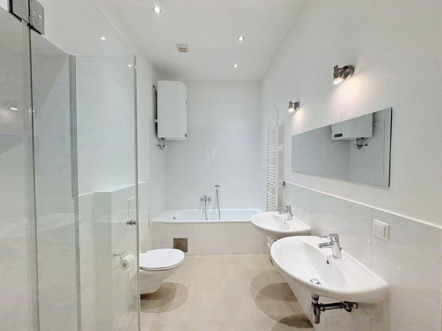 Modernes Badezimmer mit zwei Waschbecken, Badewanne und Duschkabine.
