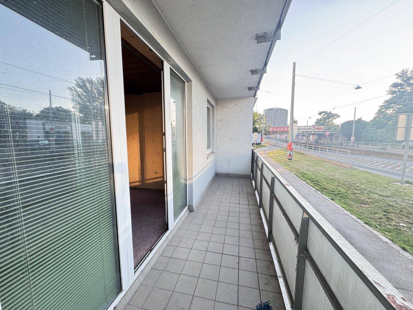 Balkon mit Fliesenboden und Blick auf die Straße sowie umliegende Gebäude.