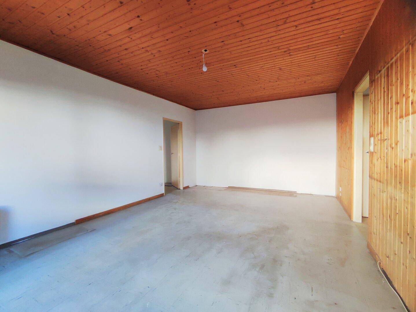 Leerer Raum mit Holzdecke und Holzpaneelen an einer Wand, bereit für die Gestaltung.