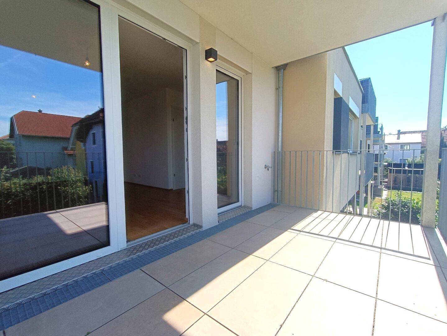 Heller Balkon mit Fliesenboden und Zugang zu den Innenräumen der Wohnung.