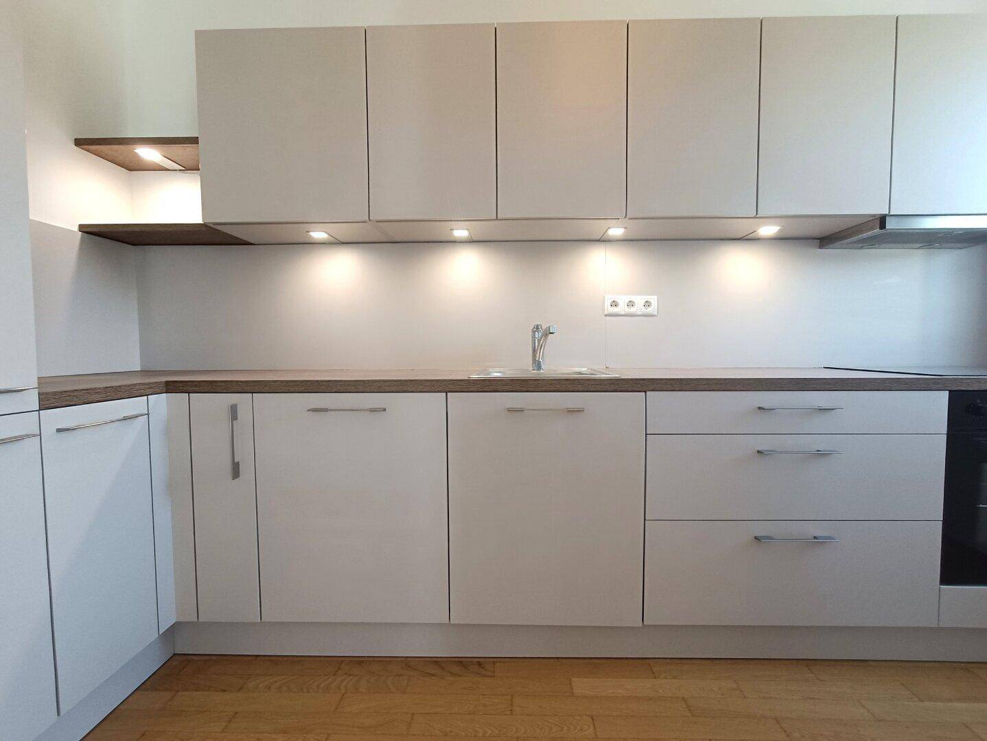 Helle Einbauküche mit viel Stauraum, Unterbauleuchten und modernem Design.