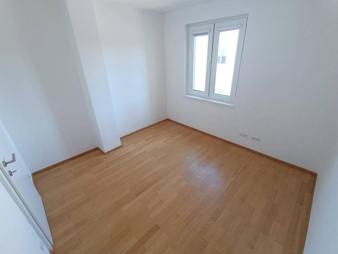 Gemütliches Schlafzimmer mit Parkettboden und einem Fenster, ideal als Kinder- oder Gästezimmer.