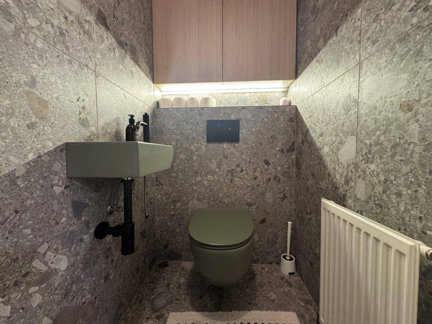 Kleines Gäste-WC mit modernen Terrazzo-Fliesen, Wand-WC und kompaktem Waschbecken.