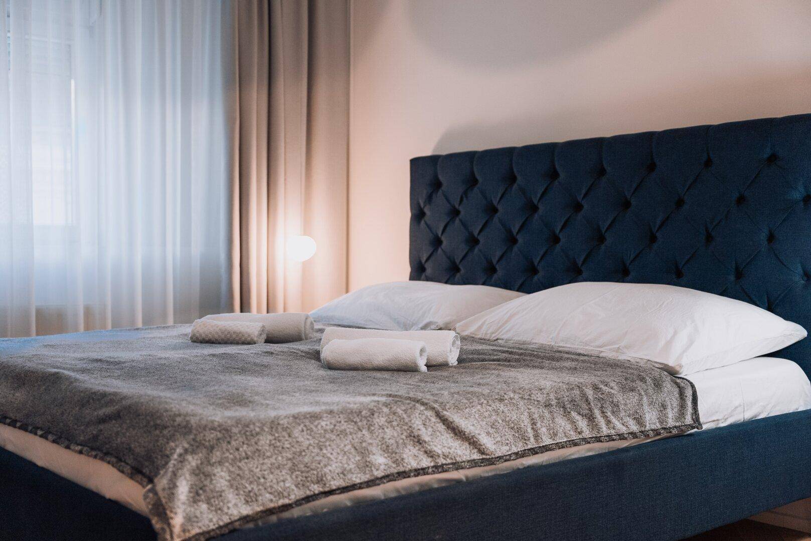 Komfortables Schlafzimmer mit großem Doppelbett, gepolstertem Kopfteil und weichen Textilien.