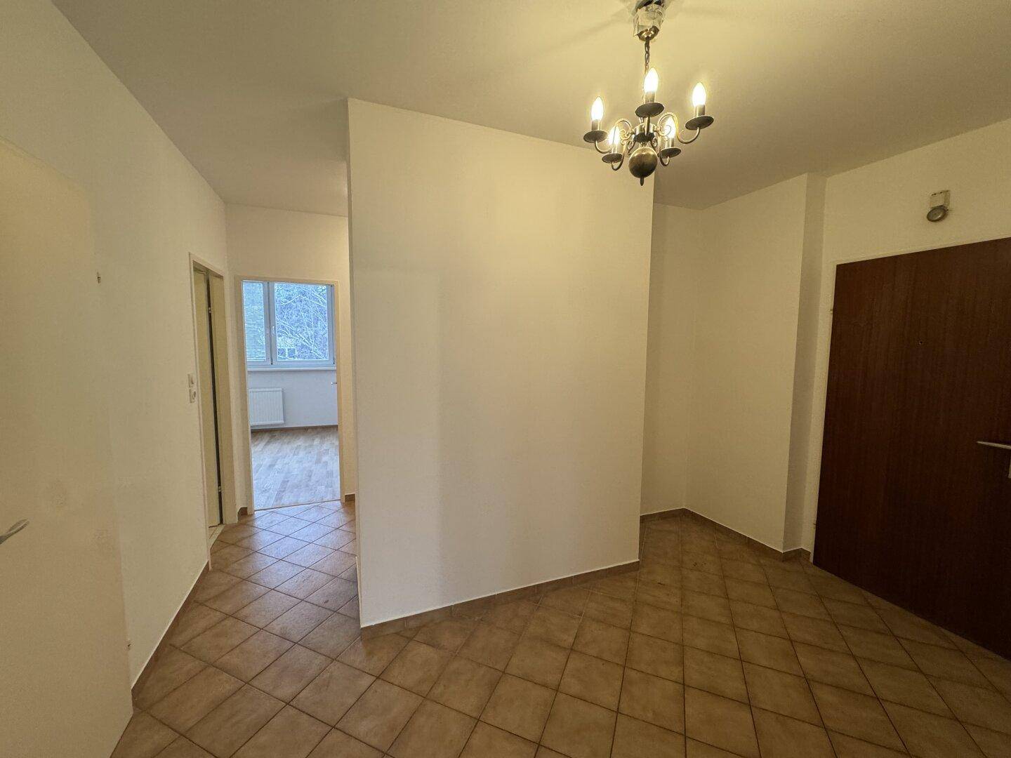 Eingangsbereich mit Fliesenboden und klassischem Kronleuchter, führt zu weiteren Räumen der Wohnung.