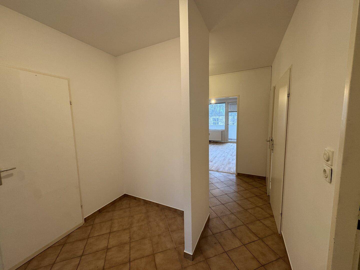 Heller Flur mit Fliesenboden und Zugang zu verschiedenen Zimmern, bietet eine klare Raumaufteilung.
