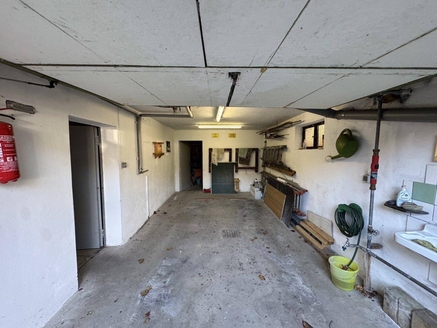 Geräumige Garage mit Betonboden, weißen Wänden und einfacher Ausstattung.