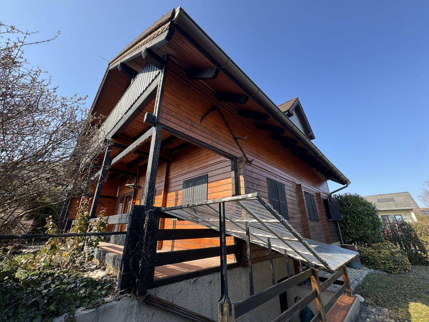 Rustikales Holzhaus im Chalet-Stil mit überdachtem Balkon und Holzbalken.