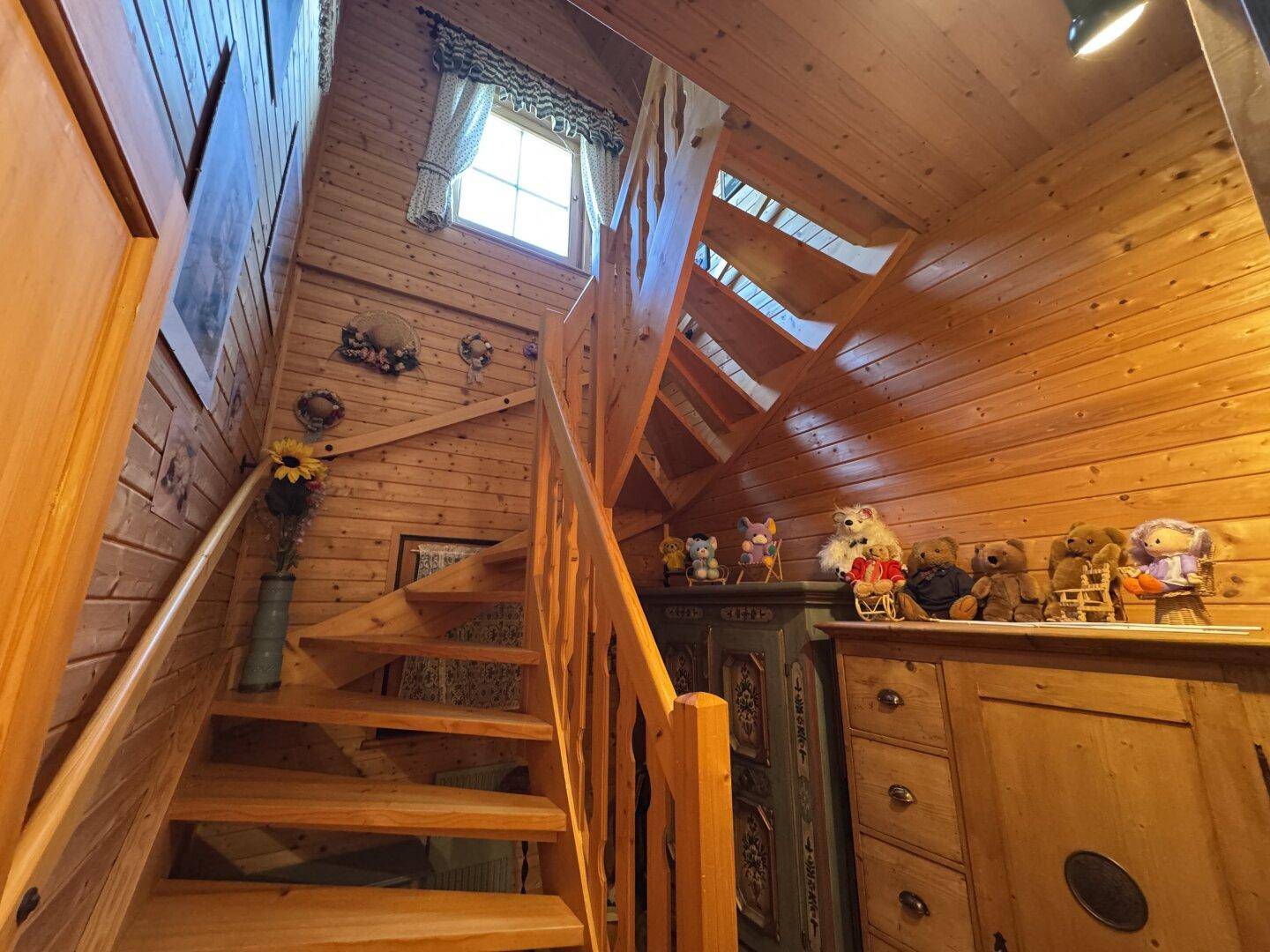 Rustikaler Treppenaufgang aus Holz mit traditionellen Dekorationen und natürlichem Lichteinfall.