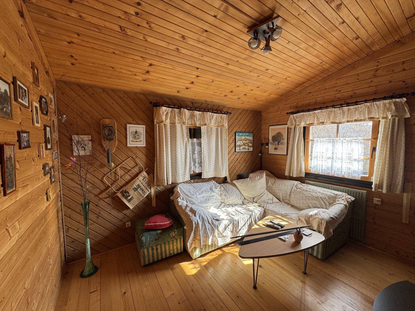 Helles Wohnzimmer mit Holzwänden, bequemer Couch und einem Fenster mit Blick ins Grüne.