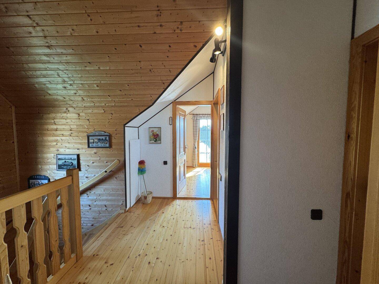 Heller Flur im Obergeschoss mit Holzgeländer und Zugang zu weiteren Zimmern des Hauses.