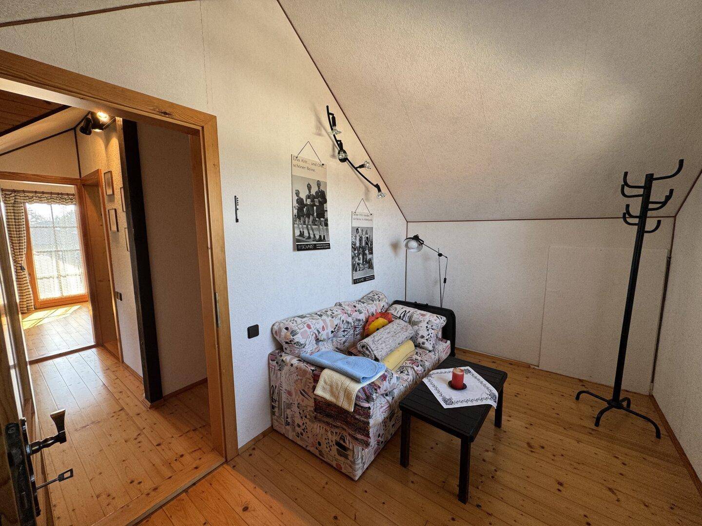 Gemütlicher Wohnbereich im Dachgeschoss mit Sofa, Beistelltisch und einer praktischen Garderobe.