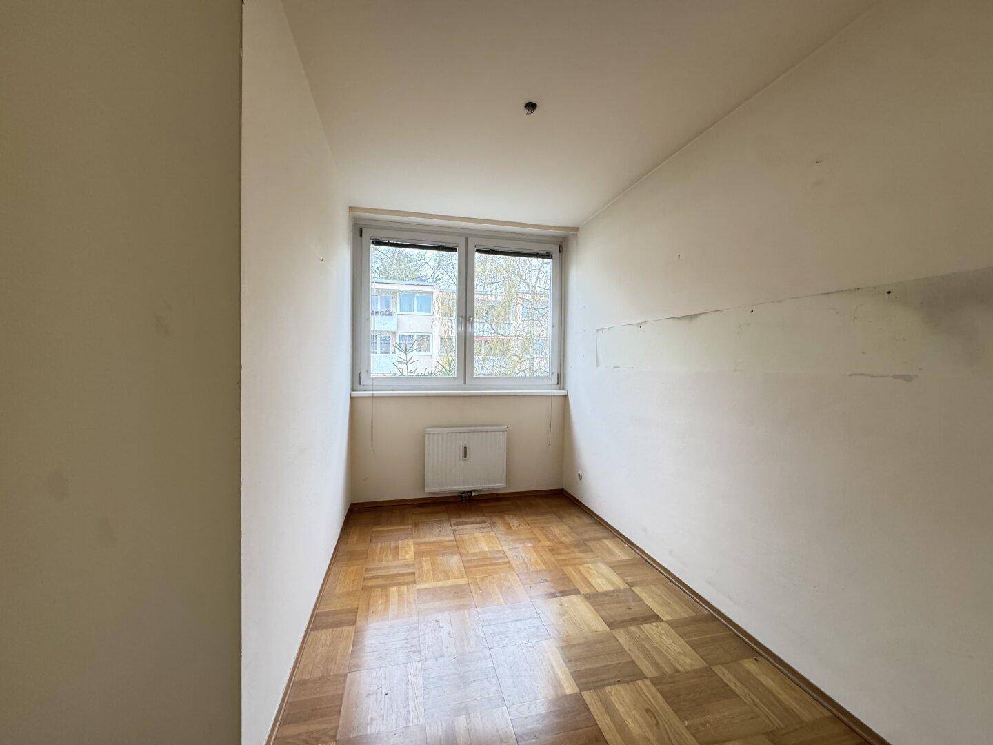 Kleiner Raum mit Parkettboden und Fenster, geeignet als Kinder- oder Arbeitszimmer.