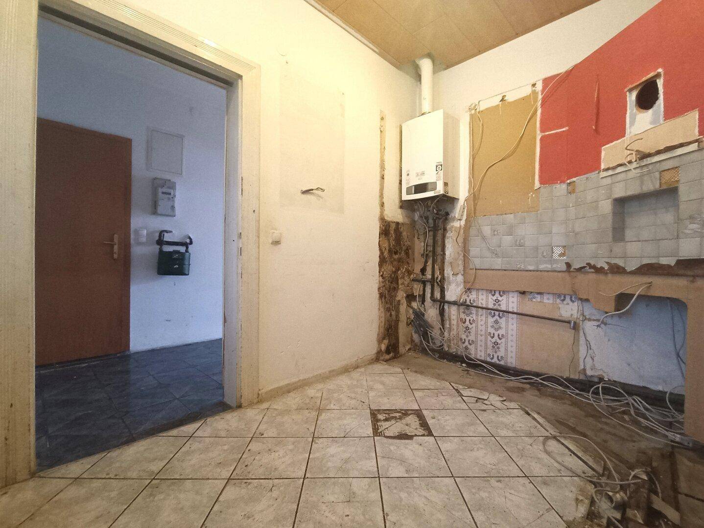 Küche im Rohzustand mit sichtbaren Installationen, bereit für den Ausbau.