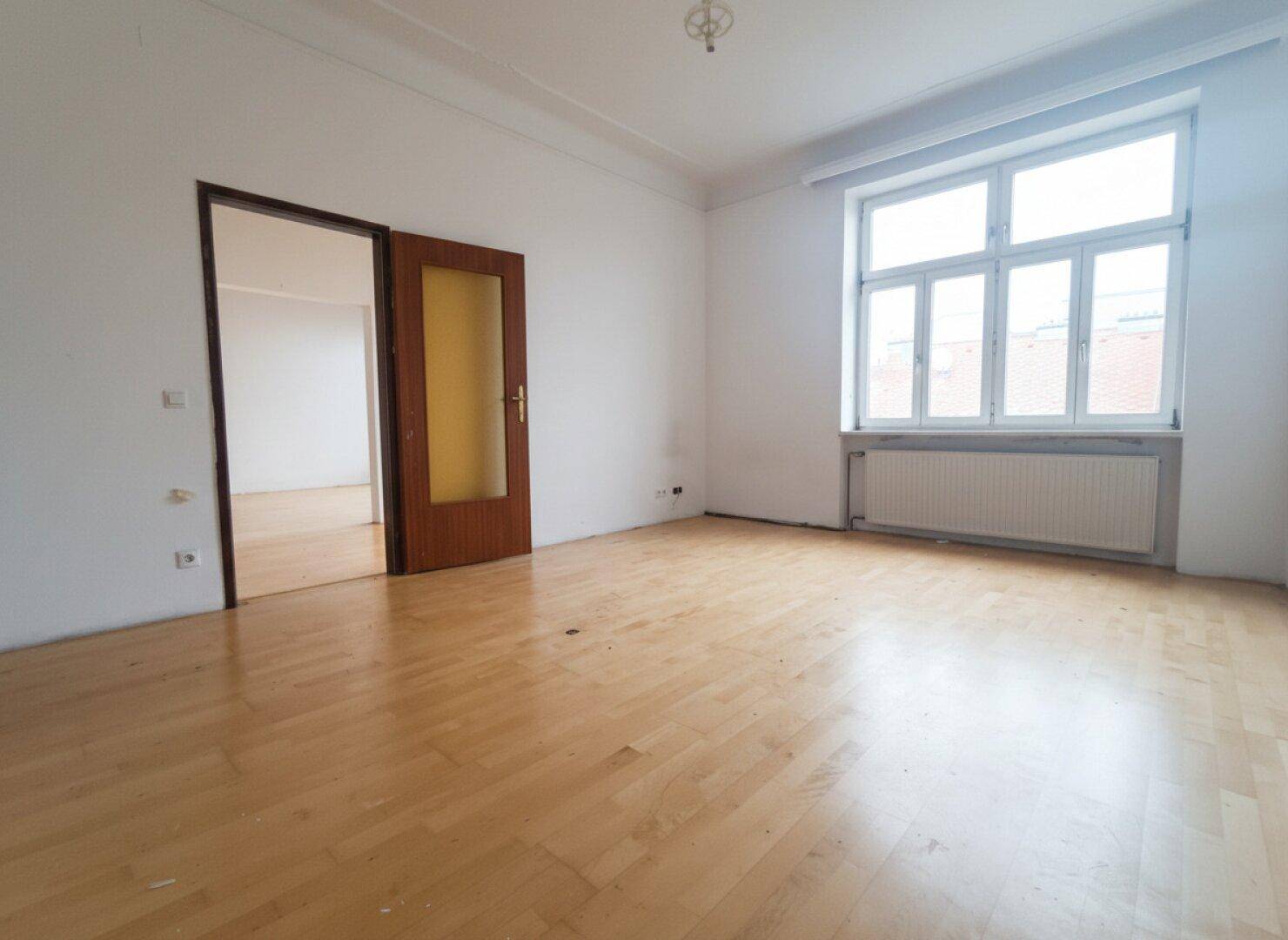 Geräumiges Zimmer mit Parkettboden, großem Fenster und Blick nach draußen.