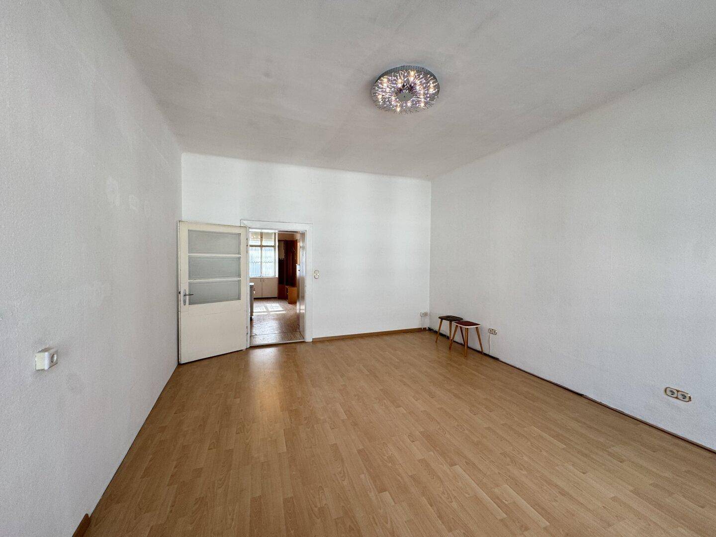 Geräumiges leeres Zimmer mit Parkettboden und Zugang zu weiteren Räumen.