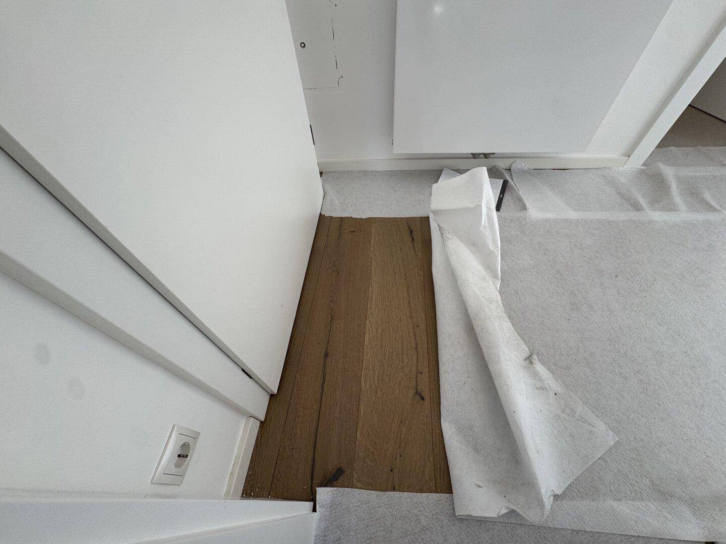 Detailaufnahme des Übergangs von Holzboden zu abgedecktem Bereich, zeigt die Parkettqualität.