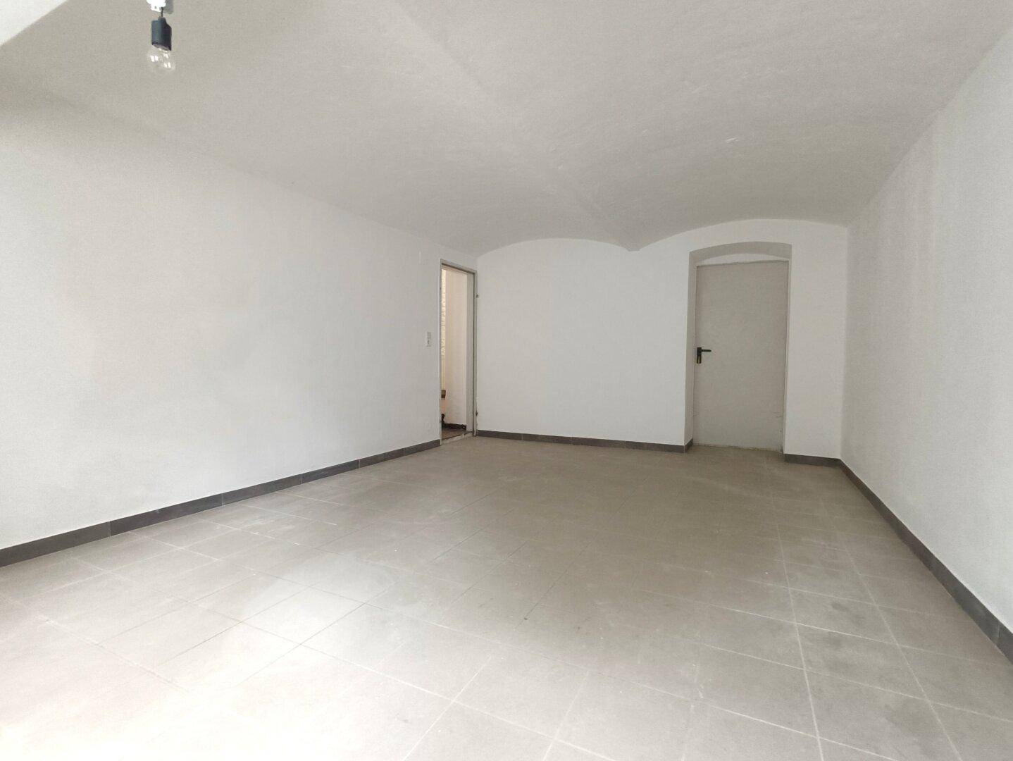 Weiterer Blick in den großen leeren Raum im Untergeschoss mit Fliesenboden und gewölbter Decke.