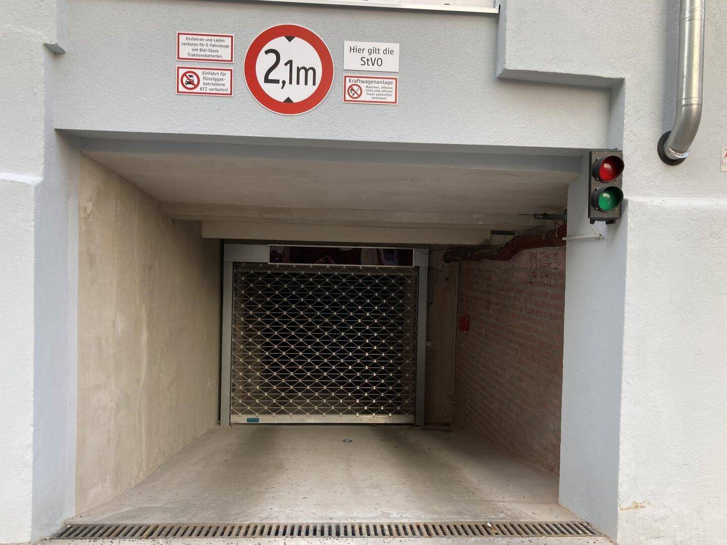 Einfahrt zur Tiefgarage mit Rolltor, Höhenbegrenzung von 2,1 Metern und Ampelsystem.