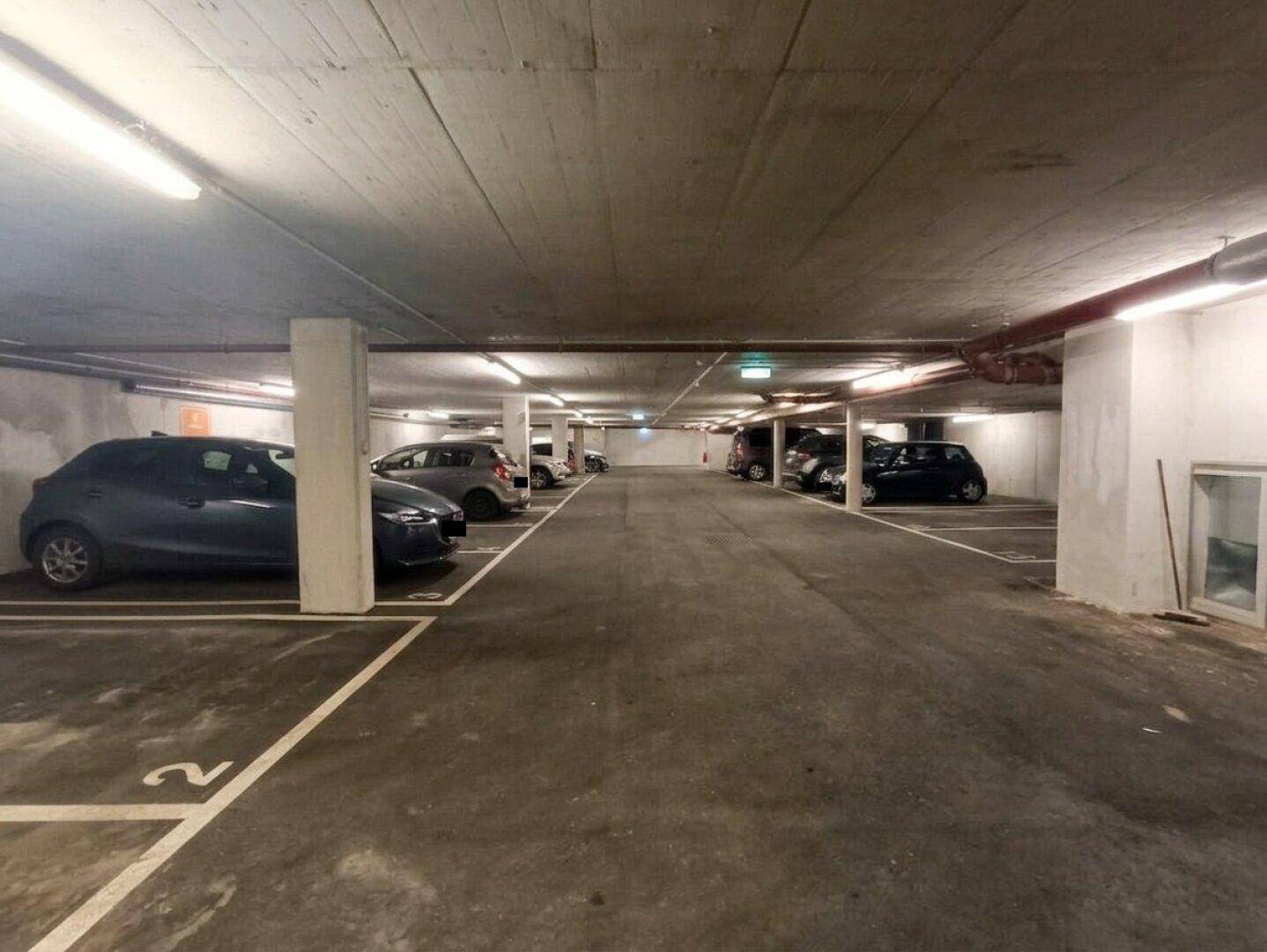 Geräumige Tiefgarage mit zahlreichen markierten Stellplätzen und heller Beleuchtung.