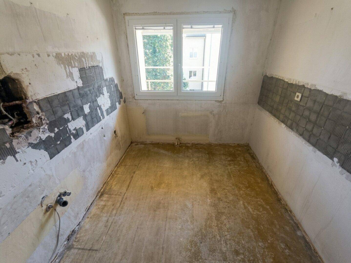 Leere Küche mit Fenster, bereit für eine neue Einrichtung und Renovierung.