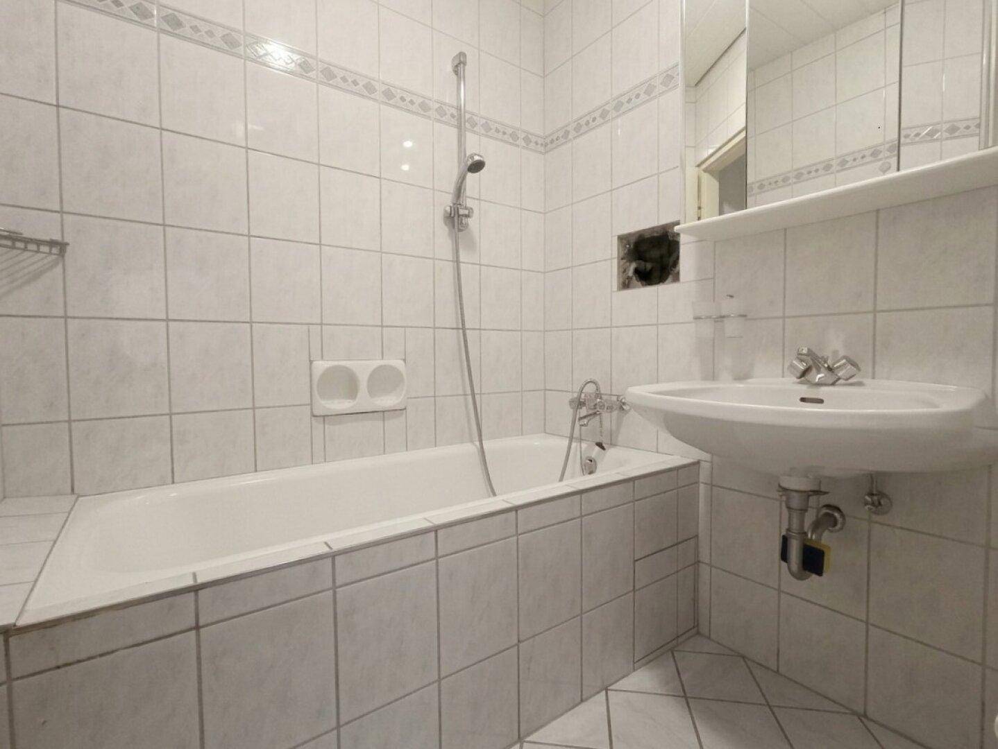 Gefliestes Badezimmer mit Badewanne, Dusche und Waschbecken, in gutem Zustand.
