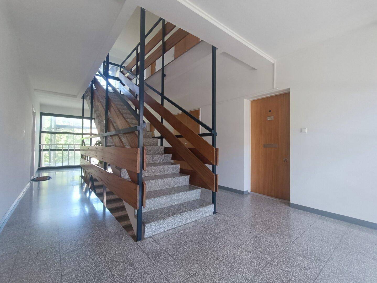 Heller Eingangsbereich mit Treppe und Fliesenboden, führt zu den oberen Etagen.