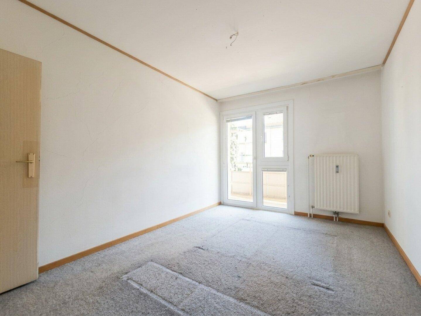 Leeres Schlafzimmer mit Teppichboden und Fenster mit Blick nach draußen.