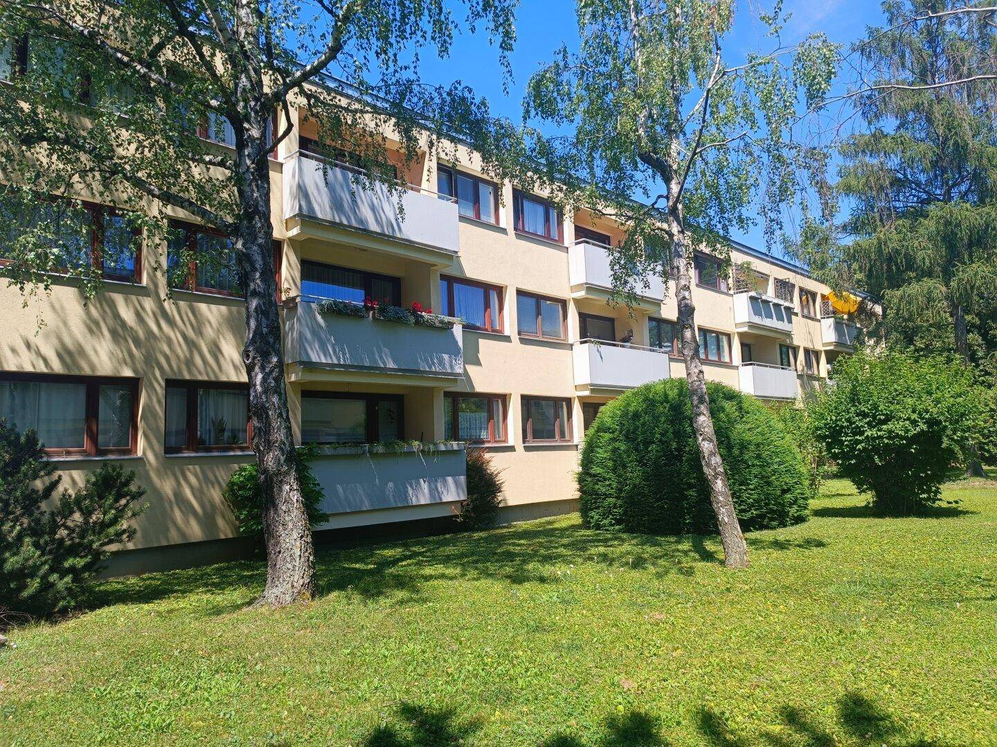Mehrfamilienhaus mit mehreren Balkonen und grüner Umgebung, gut gepflegt.