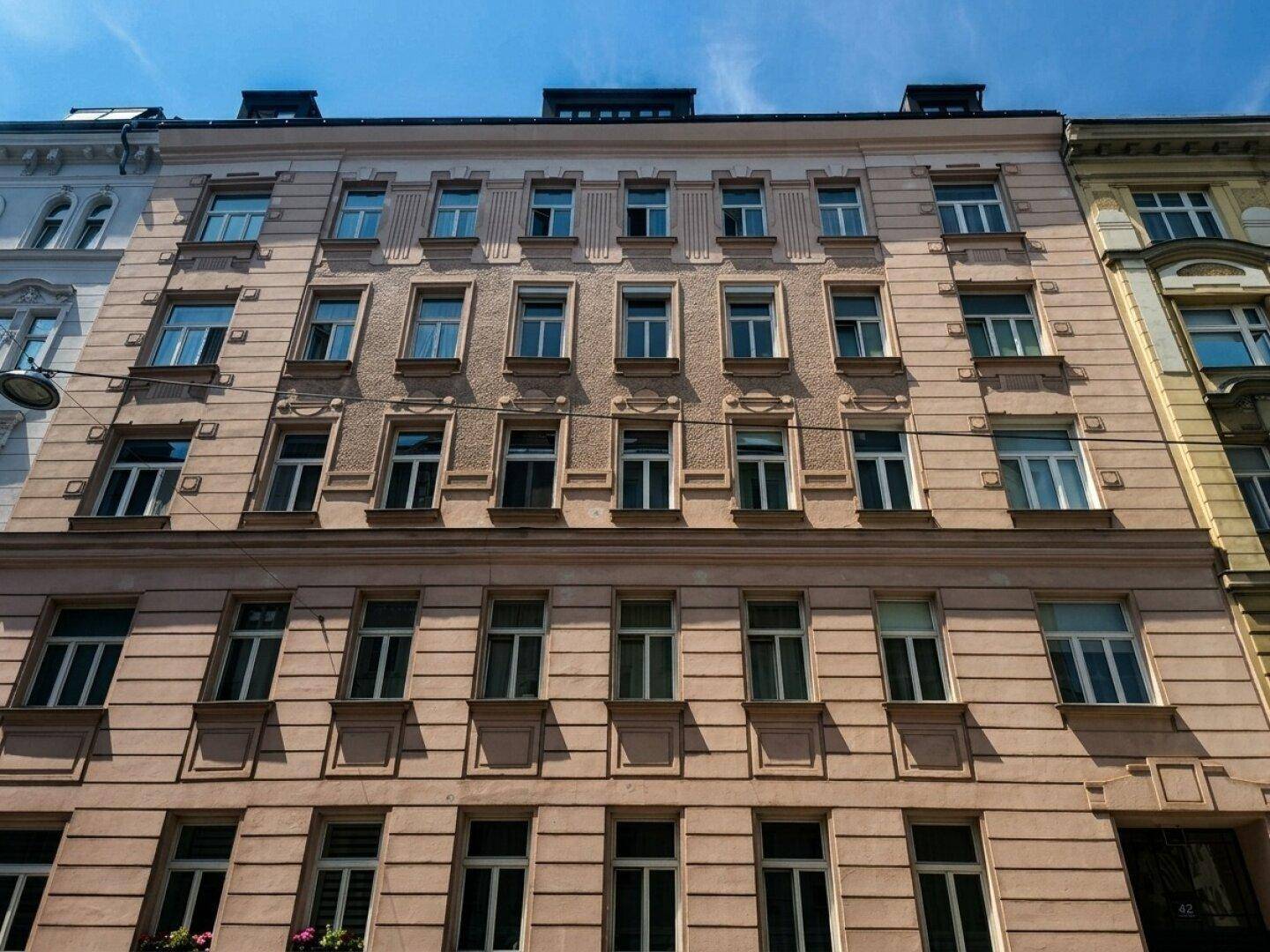 Historische Fassade eines Wohngebäudes mit zahlreichen Fenstern und klassischer Architektur.