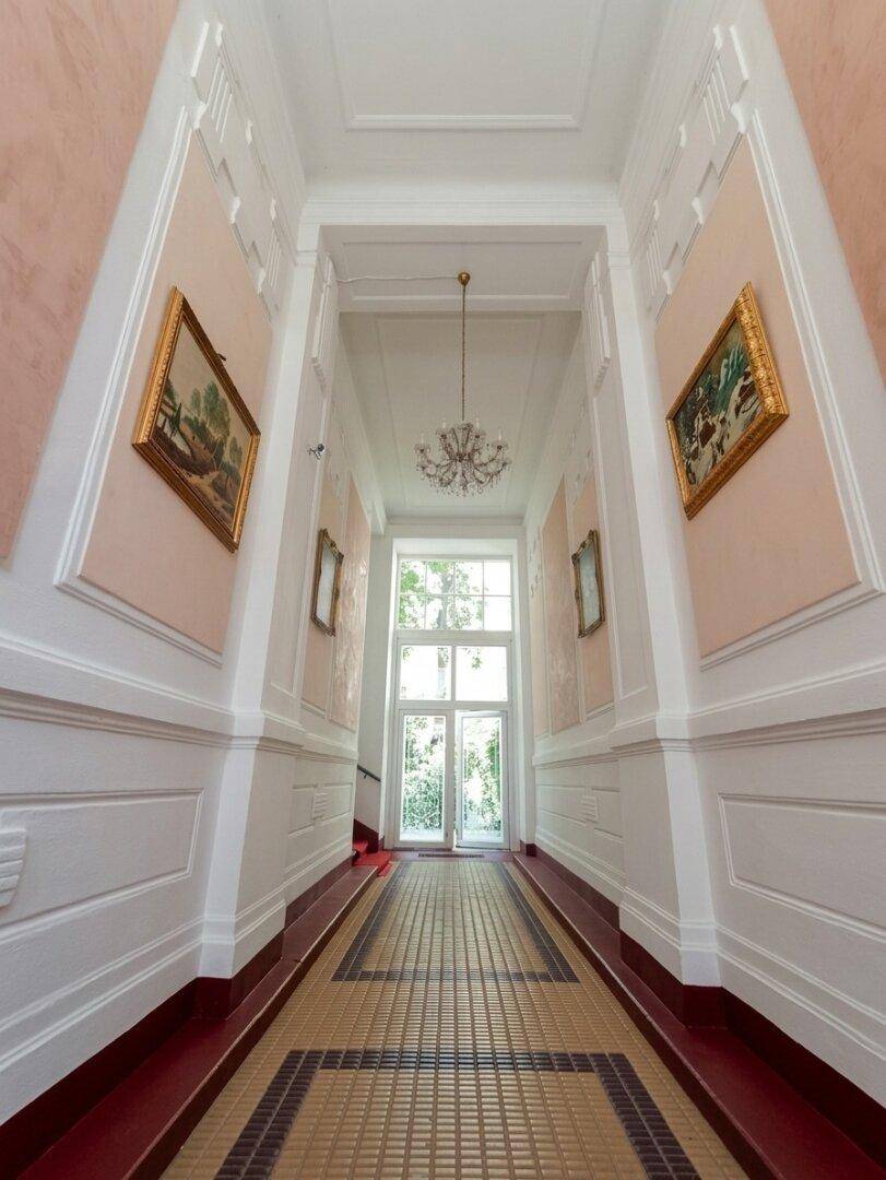 Eleganter Flur mit hohen Decken, kunstvollen Stuckarbeiten und einem gemusterten Fliesenboden.