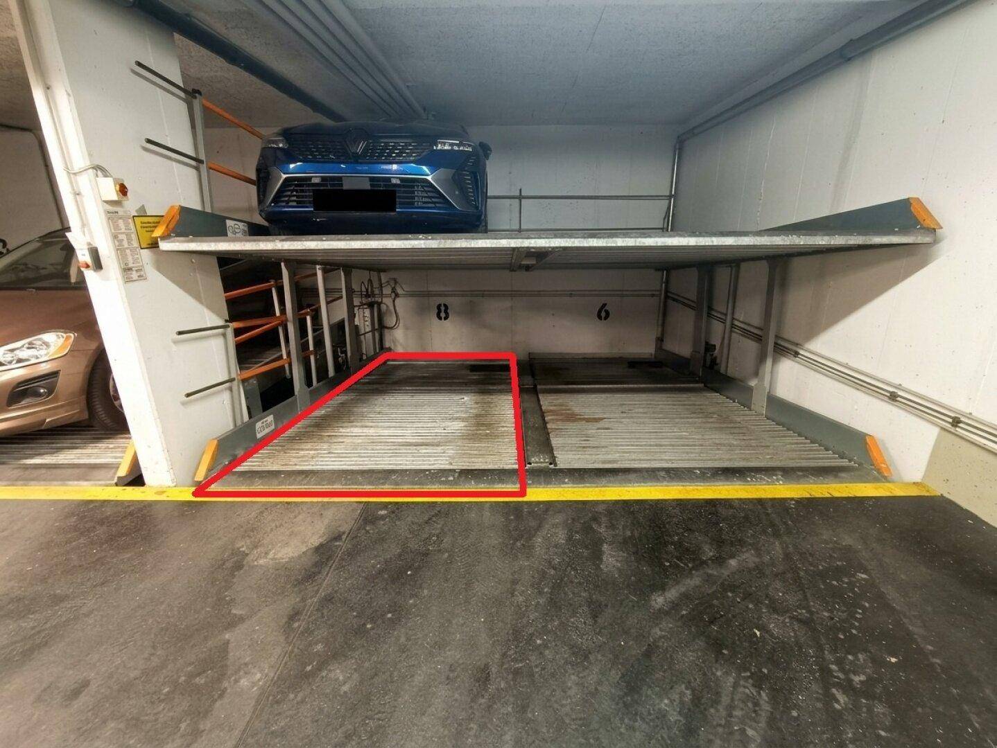 Hydraulisches Parksystem in einer Tiefgarage mit zwei Autos auf verschiedenen Ebenen, gekennzeichnet mit Nummern.