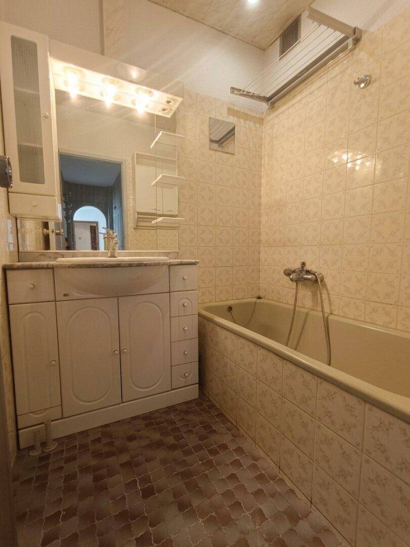 Gefliestes Badezimmer mit Badewanne, Einzelwaschbecken und Spiegelschrank im klassischen Stil.