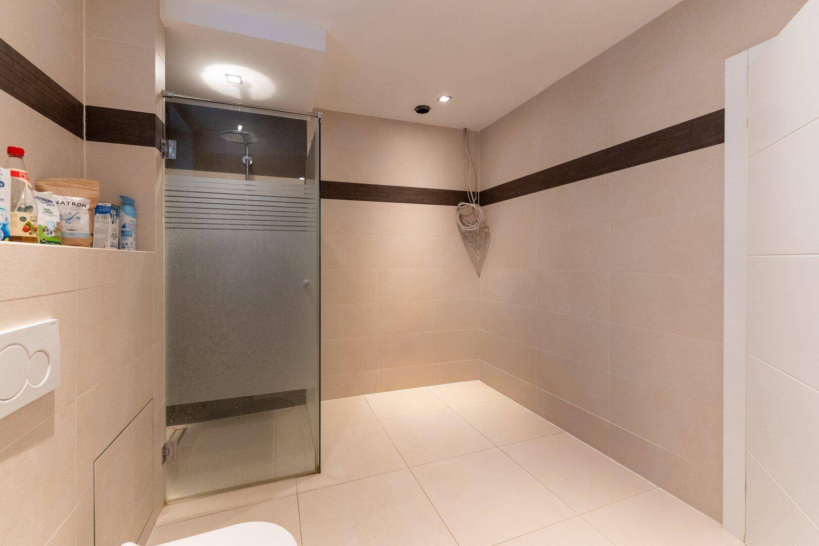 Modernes Badezimmer mit begehbarer Dusche und beigefarbenen Fliesen.