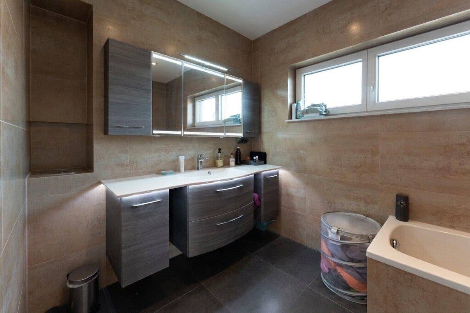 Modernes Badezimmer mit Waschtisch, Spiegelschrank und beigefarbenen Wandfliesen.