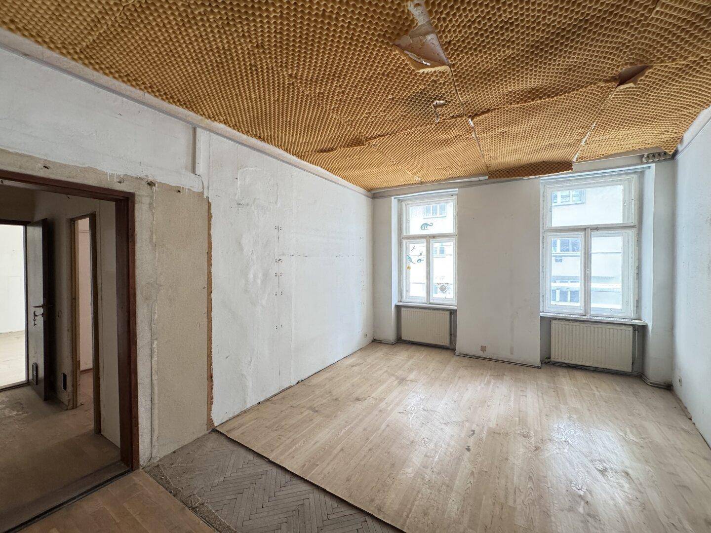Geräumiges Wohnzimmer mit renovierungsbedürftigen Wänden und Decke, bietet viel Potenzial zur Umgestaltung.