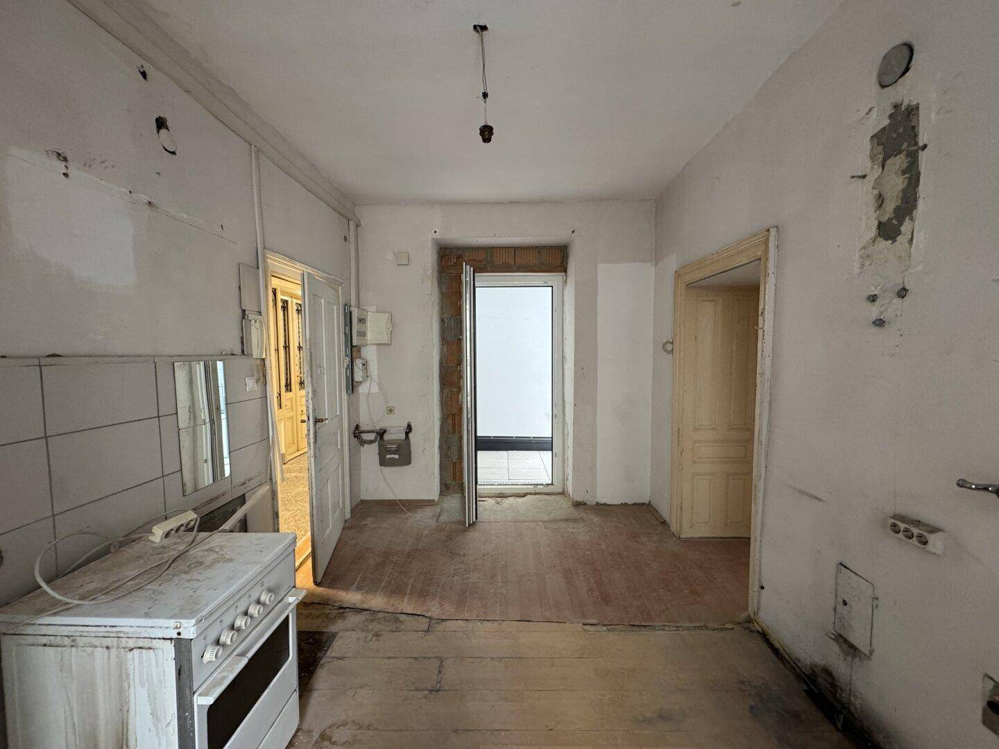 Unrenovierte Küche mit alten Fliesen und Holzboden, bereit zur Modernisierung.