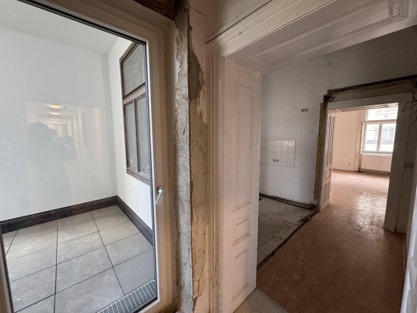 Eingangsbereich mit Blick in angrenzende Räume und Zugang zu einem kleinen Balkon.