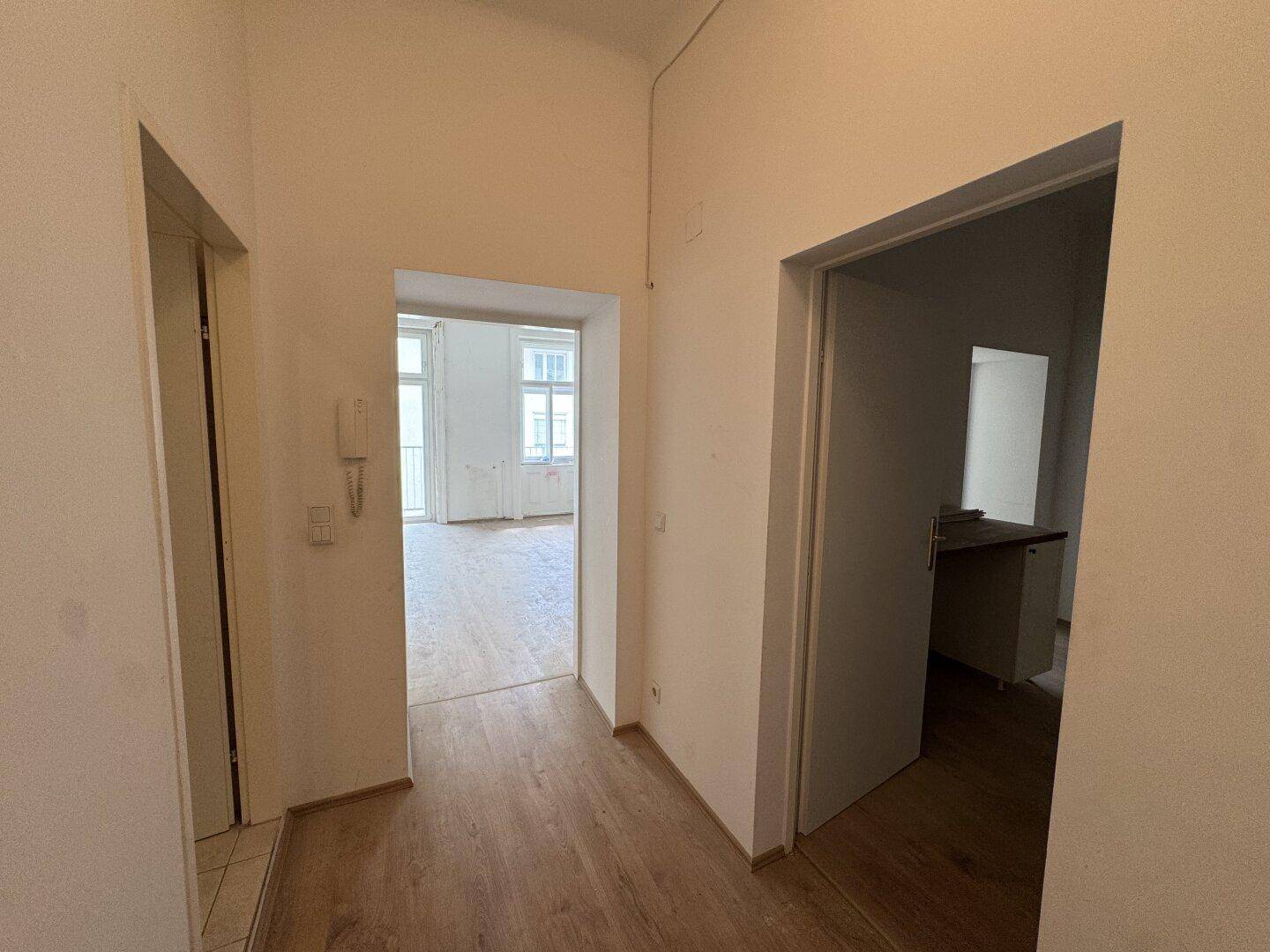 Heller Flur mit Holzboden und Zugang zu verschiedenen Zimmern der Wohnung.